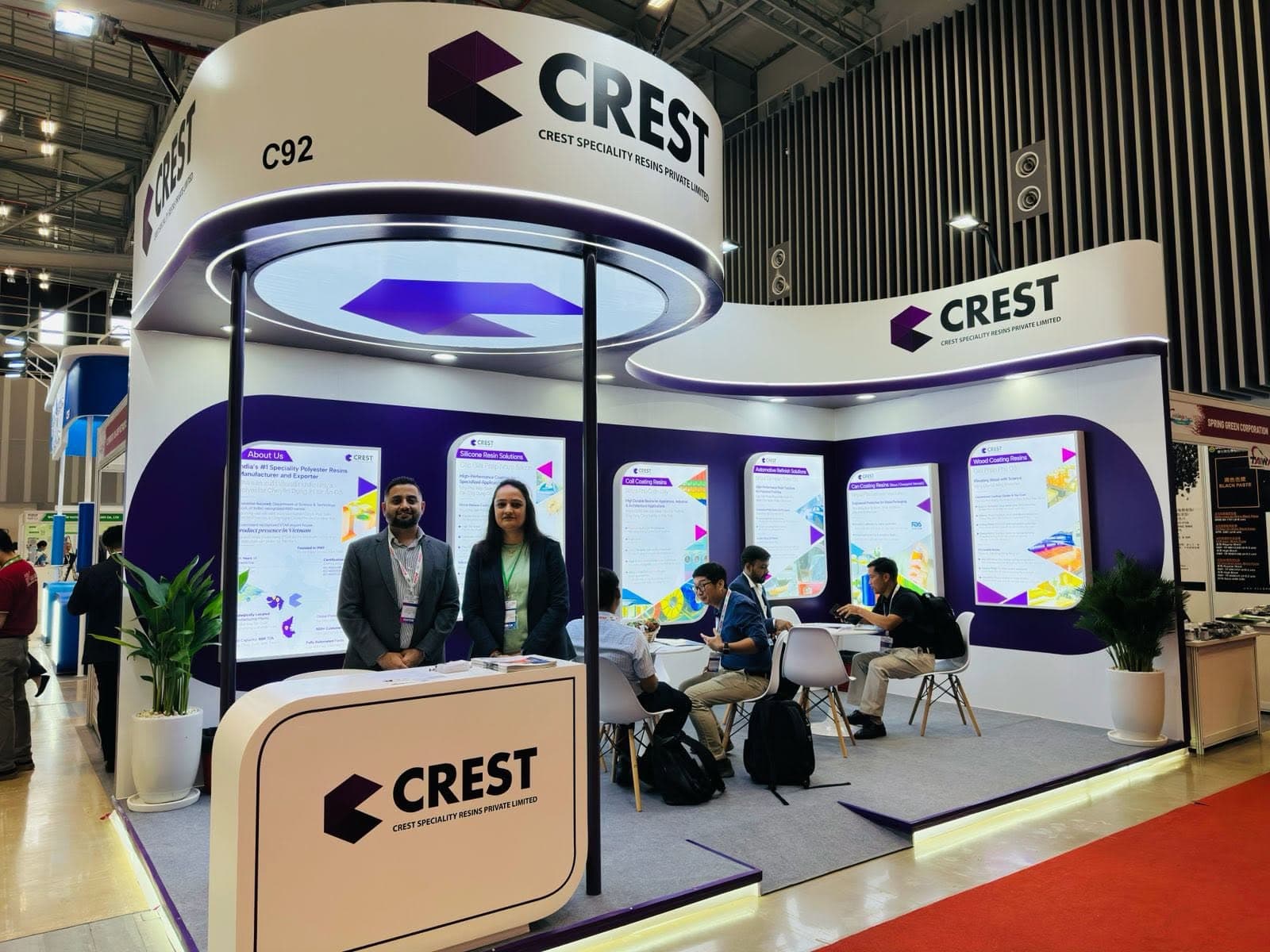 Crest Speciality Resins stand, a curved white fascia and disc ceiling over backlit product panels and meeting tables