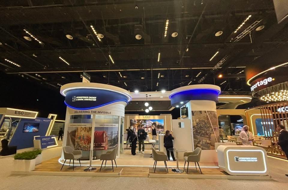 Hydropower Energy and General Construction stand, twin cylindrical towers ringed with blue cove lighting