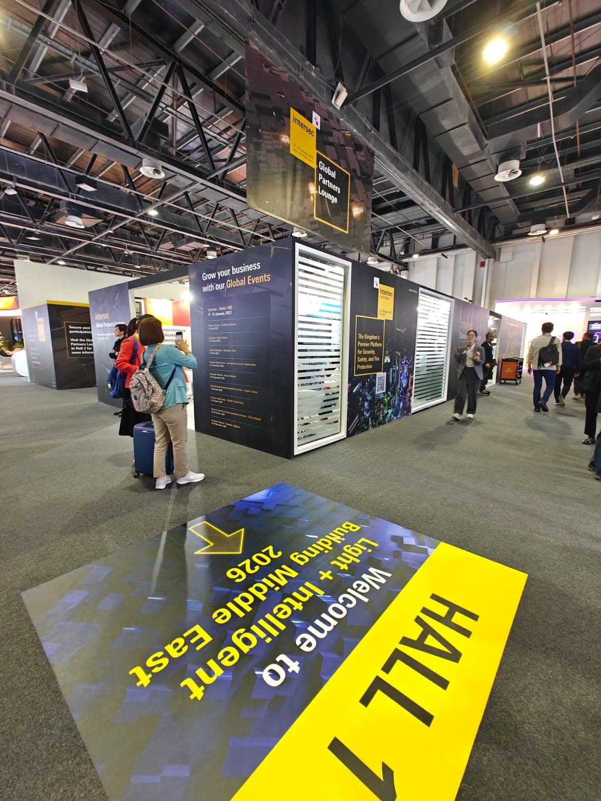 Intersec Global Partners Lounge with a suspended wayfinding banner and a printed hall-entrance floor graphic