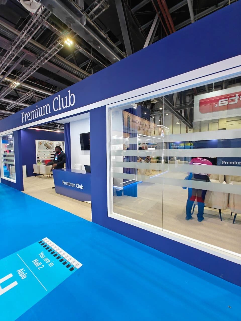 Premium Club entrance in Hall 2, a deep-blue glazed frontage with a fritted-glass privacy band