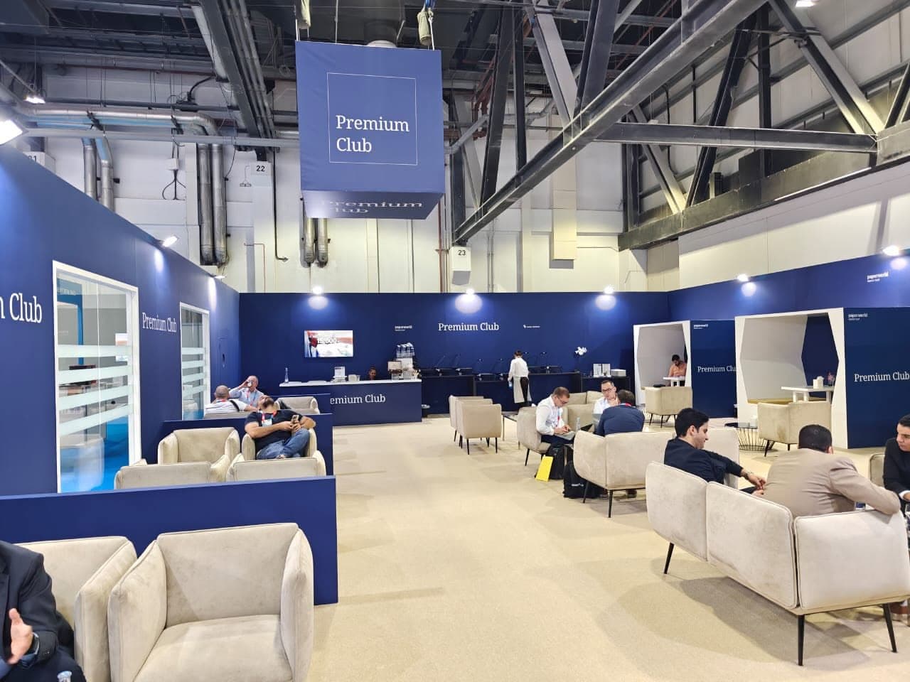 Premium Club lounge at Paperworld, a suspended branded cube above armchair groups and meeting pods