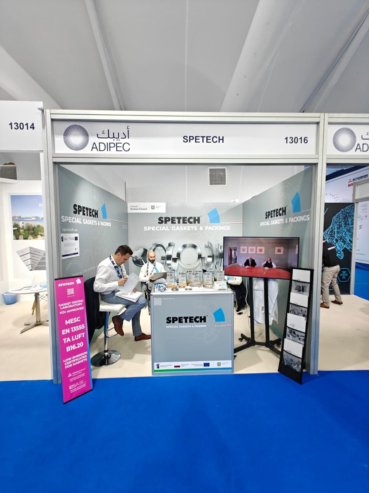 Spetech gaskets and packings stand at ADIPEC, with a brushed-steel product graphic behind a meeting counter