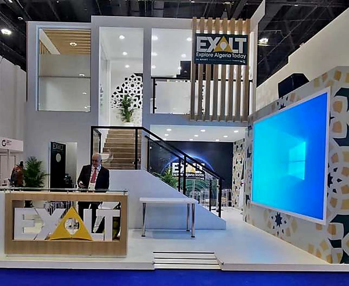 Double-deck national pavilion with a staircase to an upper meeting deck and a mashrabiya-patterned LED wall