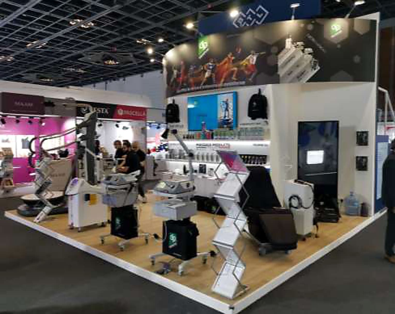 Sports-medicine and hospital equipment stand with treatment couches under an athletics graphic fascia