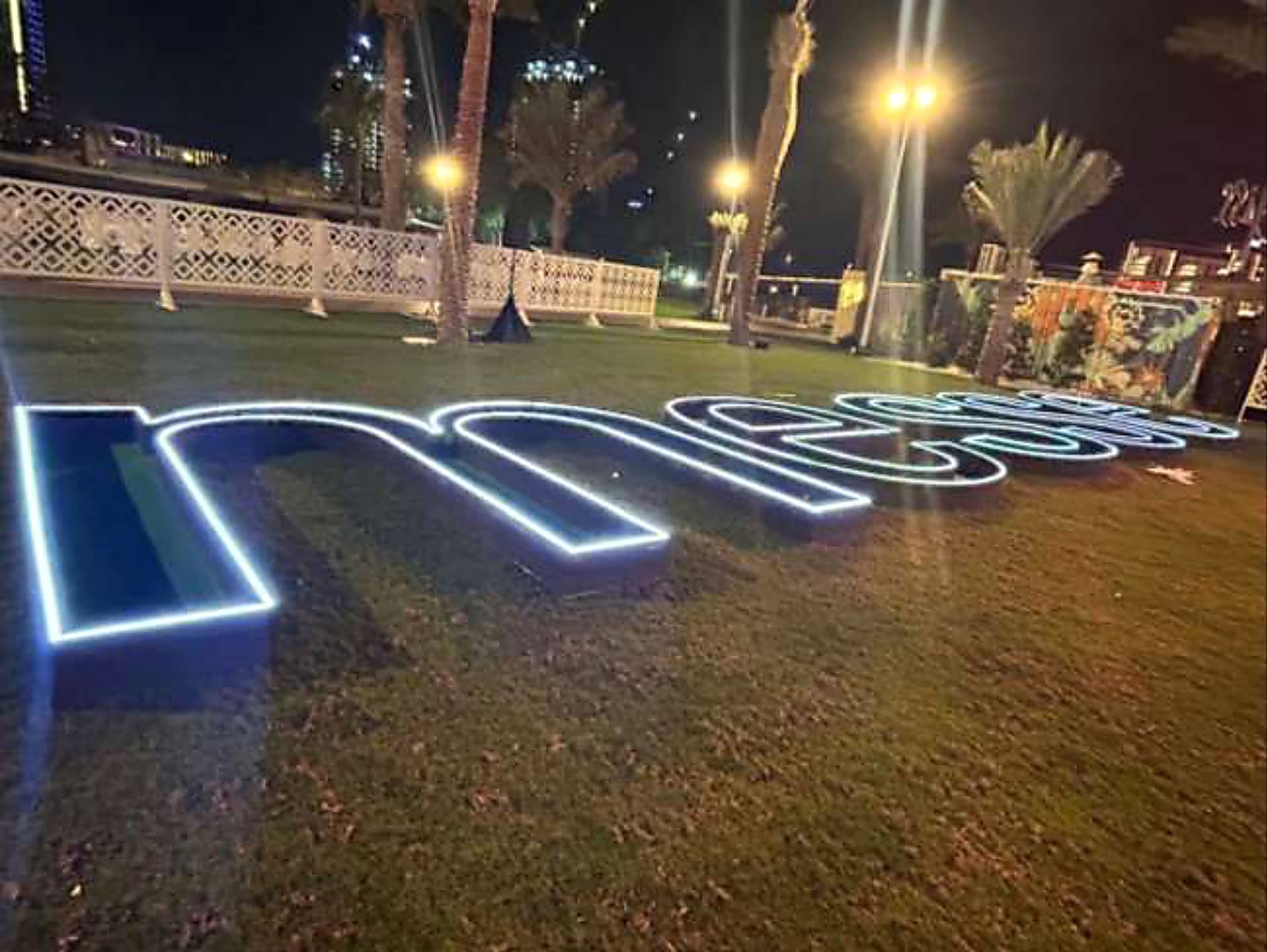 Illuminated outdoor logo letters on a lawn at an evening corporate reception